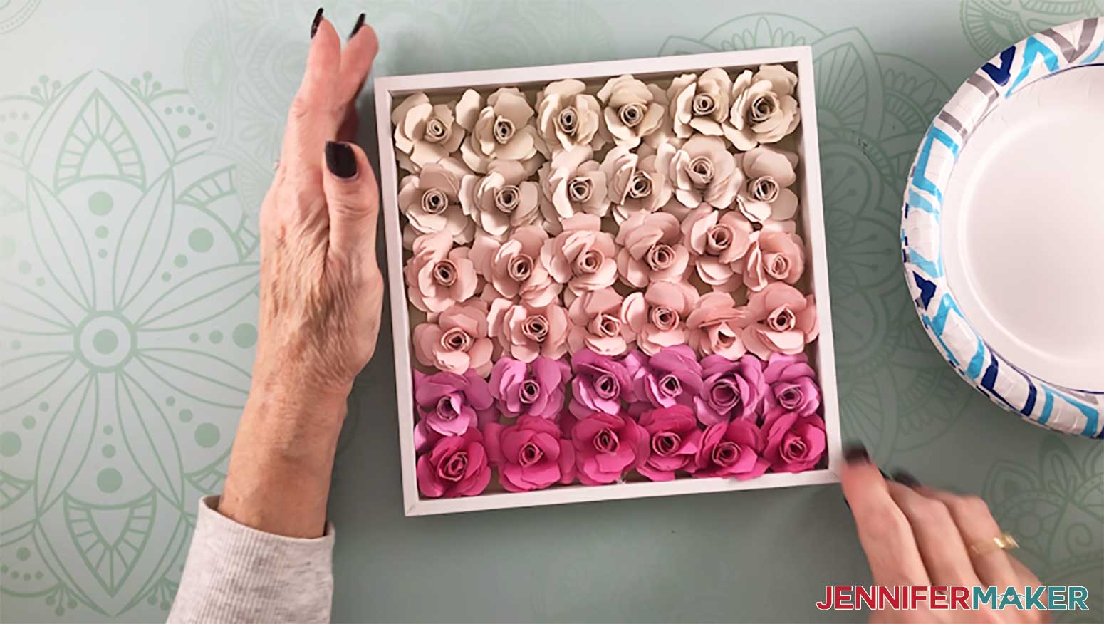 36 pink paper flowers glued inside a shadow box frame to make a paper flower shadow box