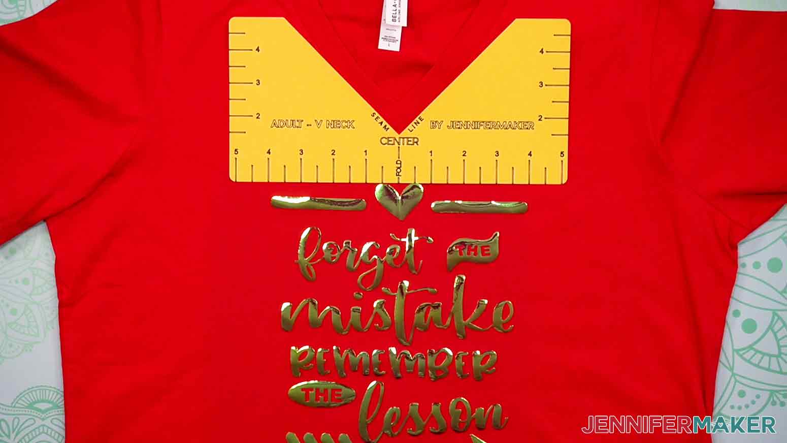 Here is an example of a red, adult v-neck T-shirt with the cardstock Adult V-Neck T-Shirt Ruler aligned under the neckline of the shirt shows the proper placement and spacing of the Remember the Lesson decal.