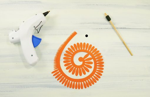 Materials for making a paper daisy: paper, hot glue gun, quilling tool