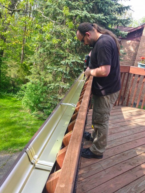 Drilling water drainage holes in the gutter garden on our deck