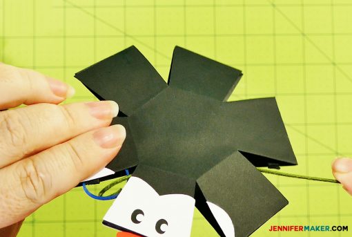 Place the rubber band in the head of the penguin paper bomb