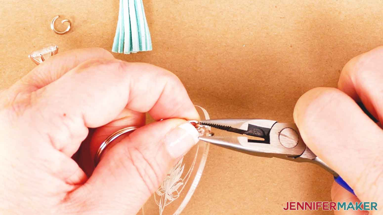 Using jewelry pliers to attach a keychain ring to the acrylic disc of your engraved acrylic keychain.