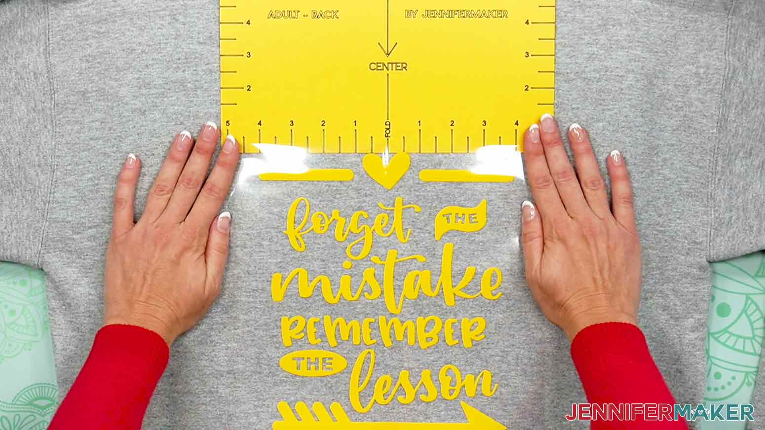 Here is how to use the cardstock Adult Back T-Shirt Ruler to align the Remember the Lesson decal on the back of a grey adult hoodie.