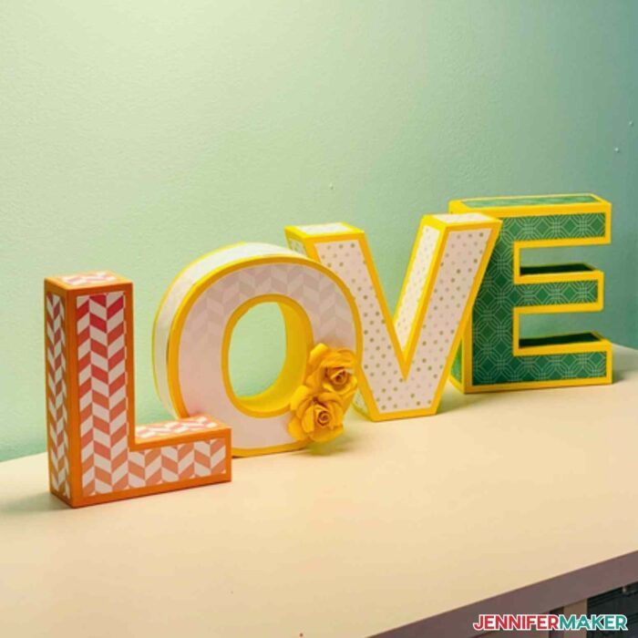 Decorative 3D Paper Letters on a white table with a green background spelling LOVE