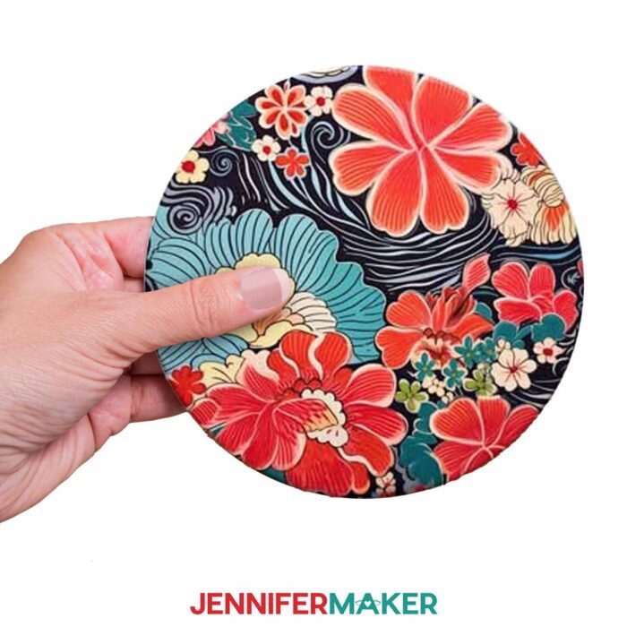 Get designs for 12 new Japanese art-inspired sublimation coasters in JenniferMaker's new blog! Jennifer holds one coaster over a white background.