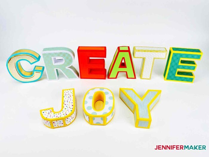 3D Paper Letters made from multiple colors of cardstock spell out the words "create joy"