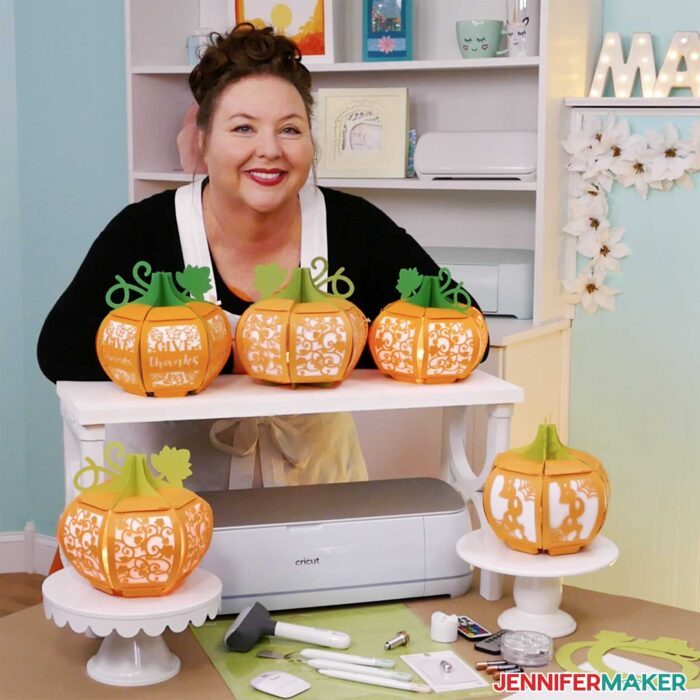 JenniferMaker and five paper pumpkin lanterns made from orange and green cardstock, plus the tools to make them