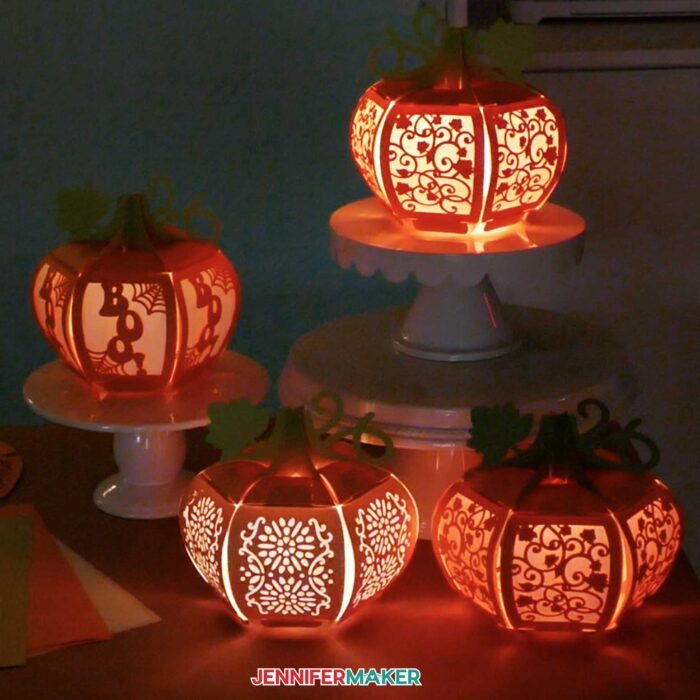 Four paper pumpkin lanterns lit up with LED lights