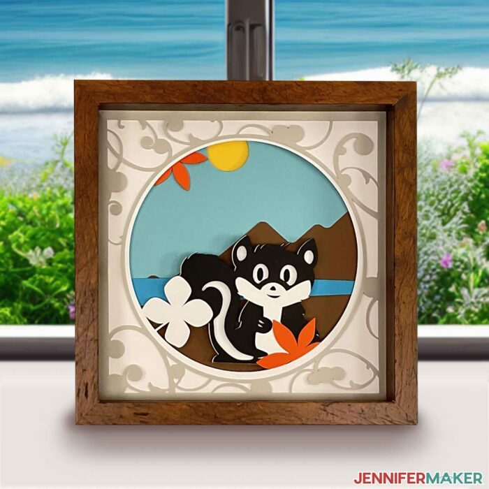 3d layered shadowbox project with skunk and summery mountain scene in front of a window showing a bright beach day.