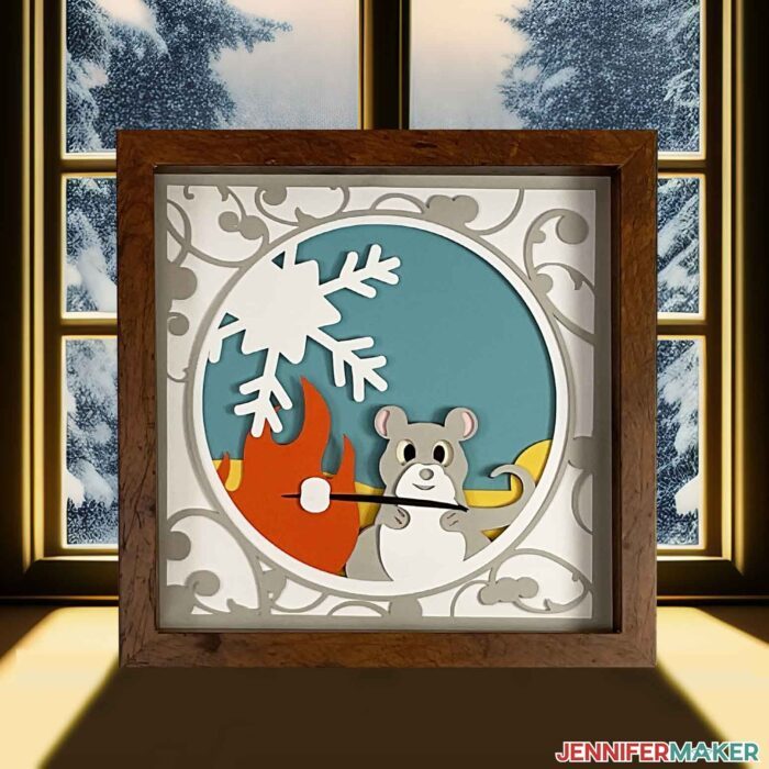 3d layered shadowbox project with a mouse roasting a marshmallow in a den in front of a window showing snow-covered trees.