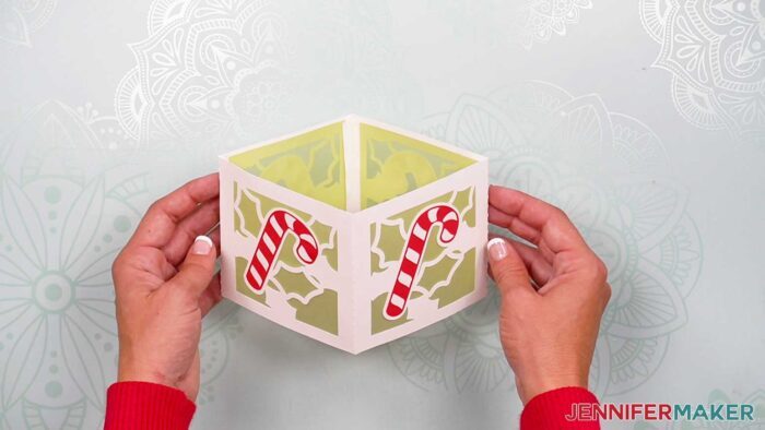 A candy cane tea light holder in white cardstock being held in hands
