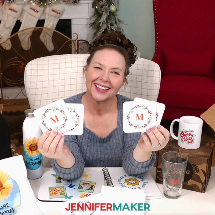 Jennifer holds up four coasters with a wreath design and a monogrammed letter M.