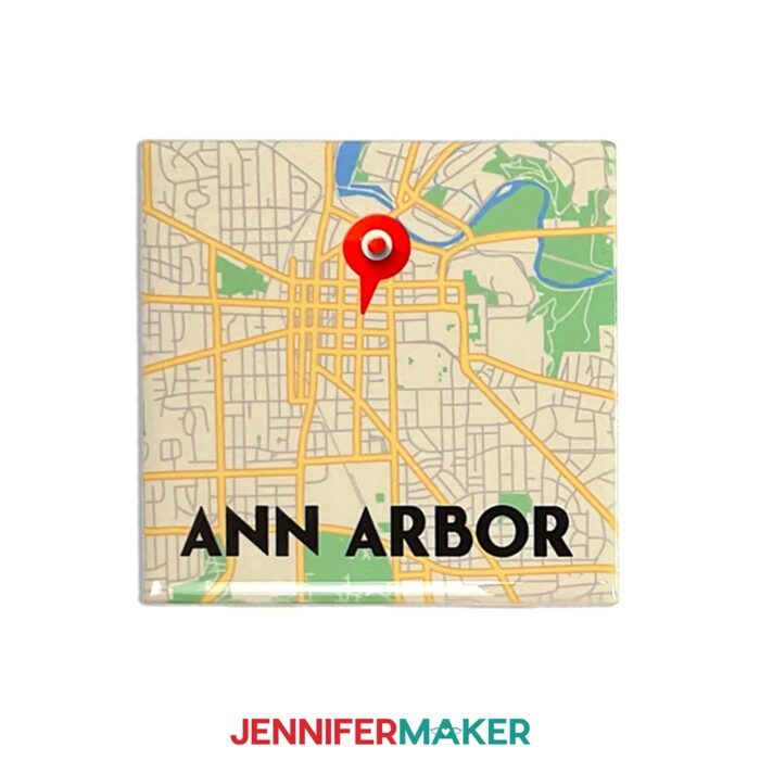 Make a custom ceramic tile map with sublimation with Jennifer Maker's tutorial! Image description: A ceramic tile map sits on a white surface. Map is of Ann Arbor, Michigan, and features a cute location icon you can add in Cricut Design Space.