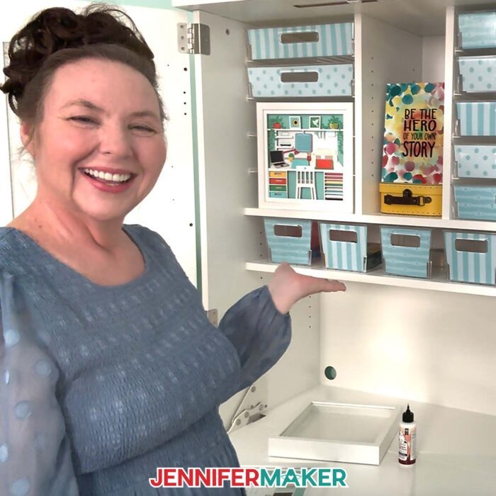 Jennifer Maker shows off the craft room shadow box design she made, which sits on display inside her Dream Box craft storage cabinet