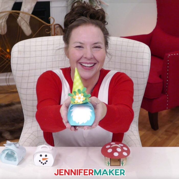 Jennifer Maker sits at her craft table, showing off Curvy Keepsake Boxes and holding the gnome box