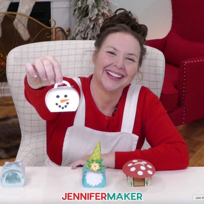 Jennifer Maker sits at her craft table, showing off Curvy Keepsake Boxes and holding the snowman box