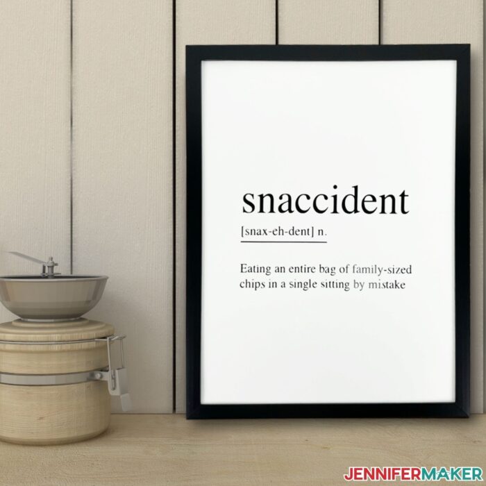 DIY kitchen wall sign sitting on a counter with the word "snaccident" on it