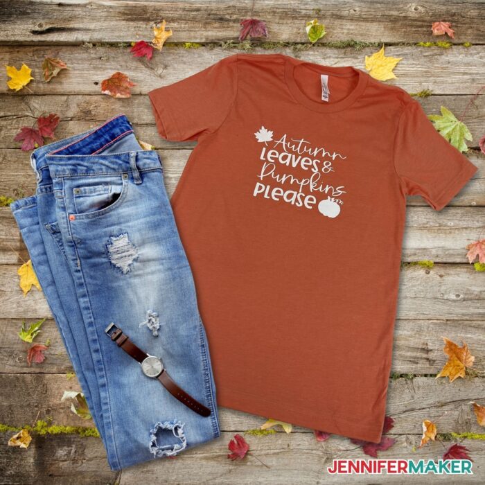 DIY Screen Printed Shirt with jeans beside it on a wooden background surrounded by autumn leaves