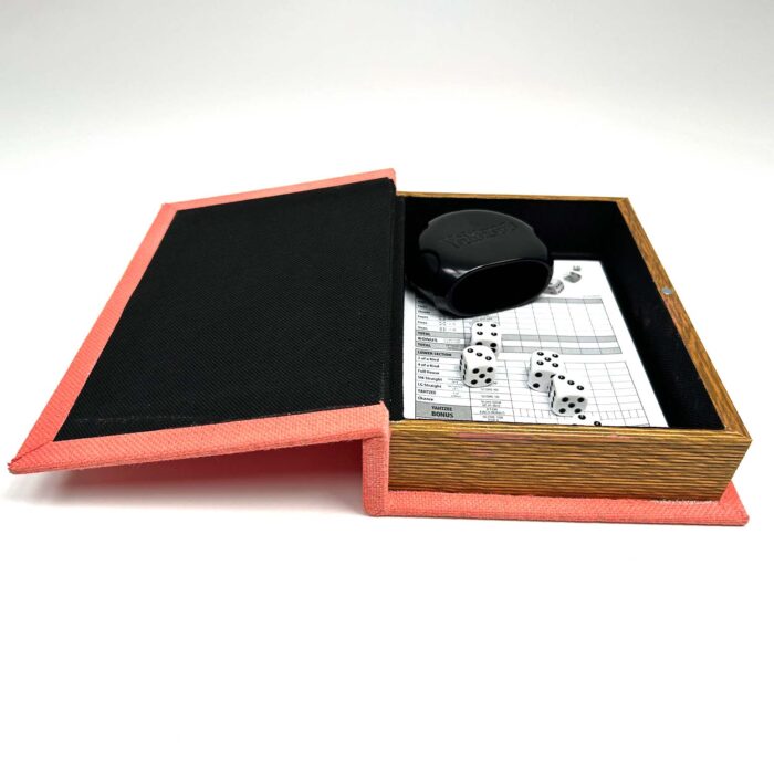Learn how to make a DIY Board Game Box to store all your game pieces with JenniferMaker's tutorial! A painted red box that looks like a hollow book lies open. A scorecard pad and the other pieces for a dice game called Yahtzee are inside the box.