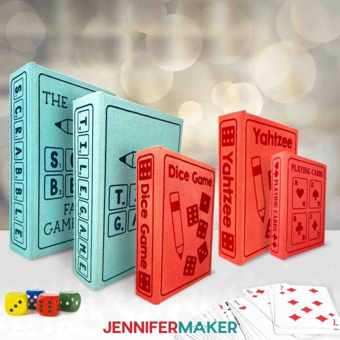 Learn how to make a DIY Board Game Box to store all your game pieces with JenniferMaker's tutorial! Five painted book boxes with iron-on vinyl labels are stood on end on a table. There are blue and red boxes of varying sizes, each labeled with a game title.