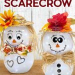 Learn how to make a Dollar Tree scarecrow under $10! Two adorable light-up scarecrow crafts sit on a wooden table. Each has an autumn hat, cute accessories, and different vinyl faces and details.