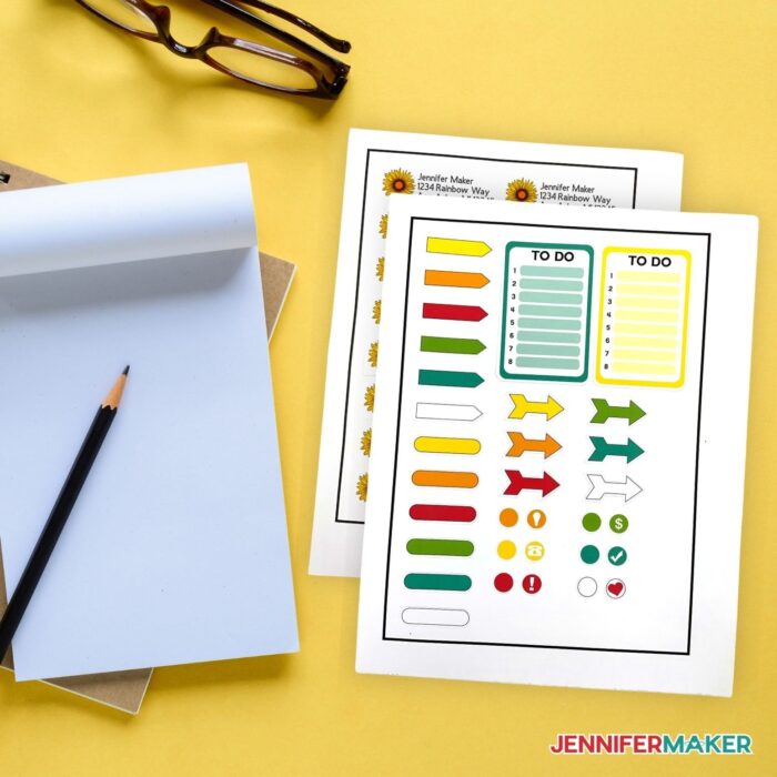 Sticker sheets on a yellow background next to a notepad and pencil