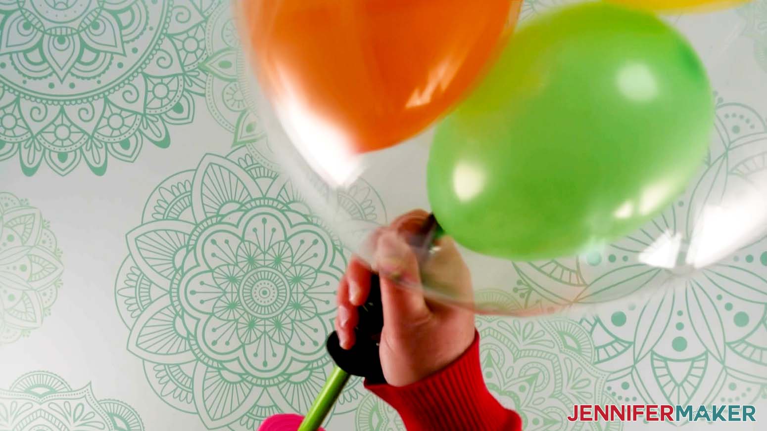 A closeup photo showing a Bobo balloon being inflated with a hand pump with several small colored balloons inflated inside