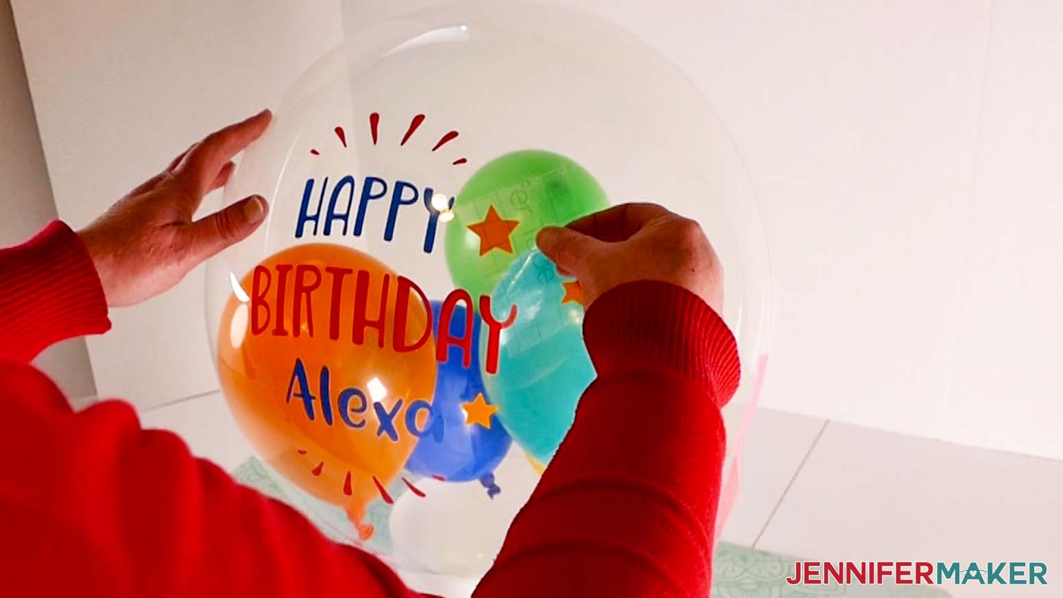 A photo showing a piece of transfer tape being removed from a vinyl balloon bouquet decal on an inflated Bobo balloon