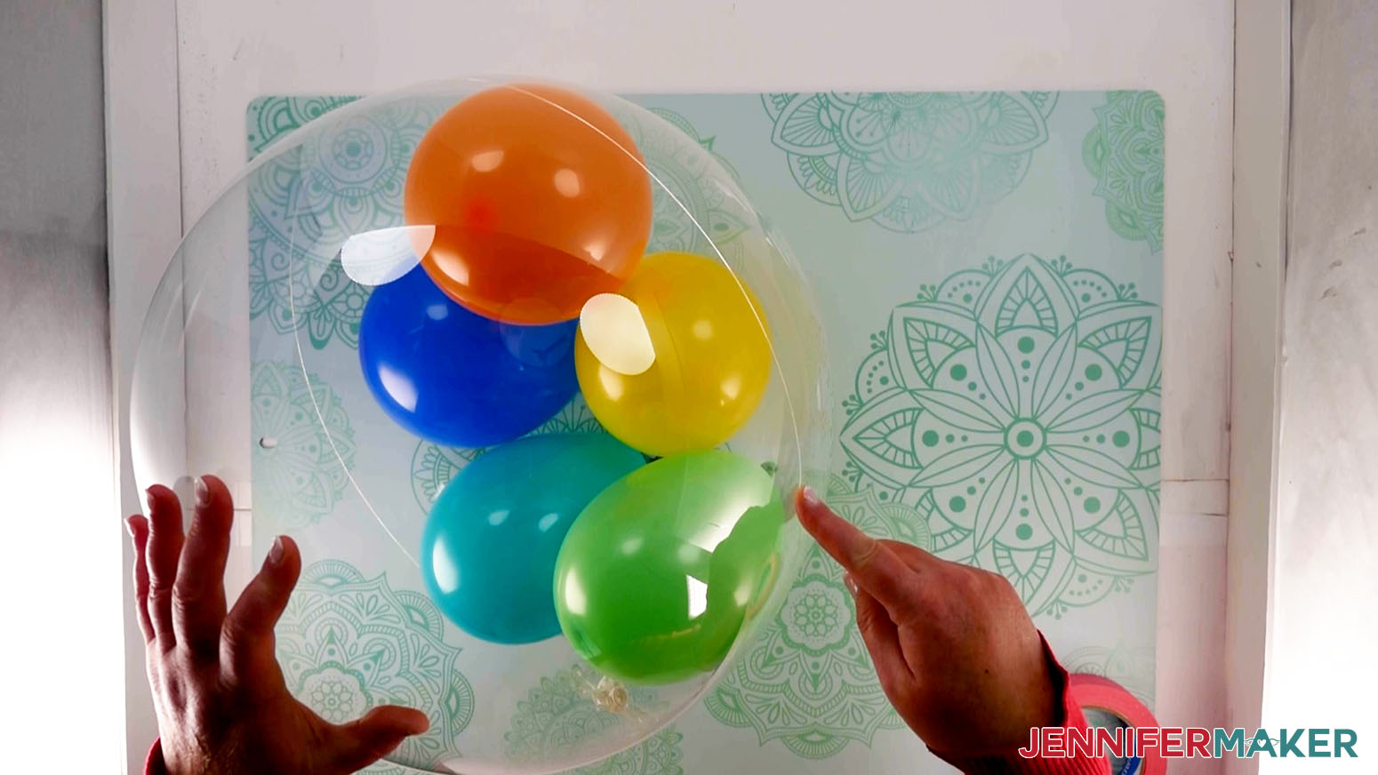 An overhead photo showing an inflated Bobo balloon being held with one hand while another hand points to the seam on the right side of the balloon