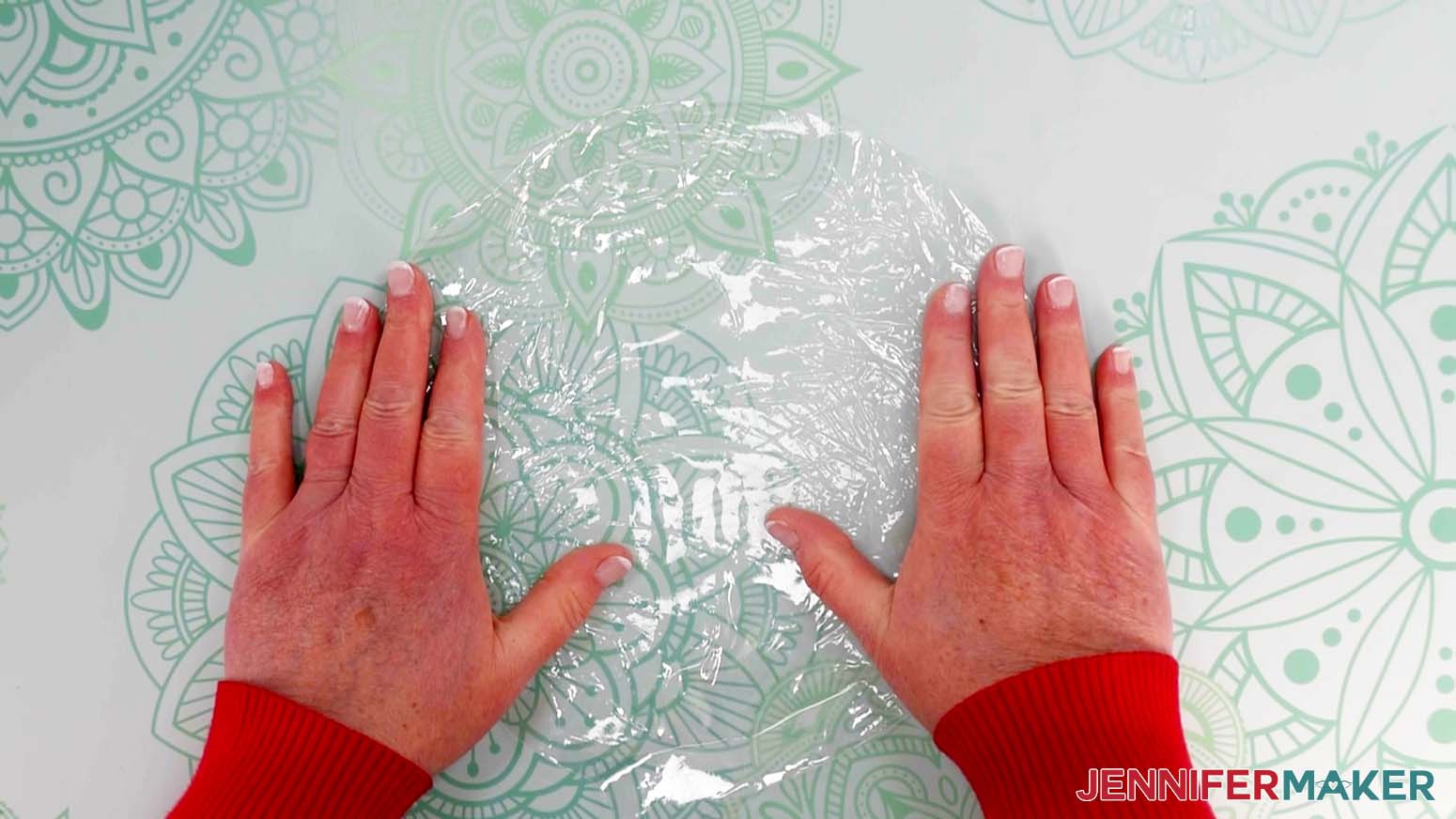 An overhead photo showing a stretched Bobo balloon with two hands keeping it flat on the work surface