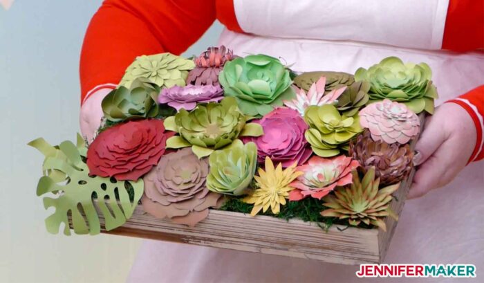 Jennifer Maker holding a wooden tray of paper succulents