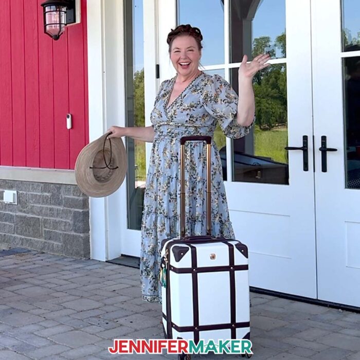 Jennifer Maker stands waving in a dress on the porch of Maker Farm, a white suitcase with a sublimated luggage tag at her side. Learn how to Make A QR Code With Canva in the free tutorial
