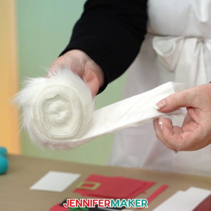 Unrolling a strip of white faux fur to use as the beard on a Santa purse gift bag.