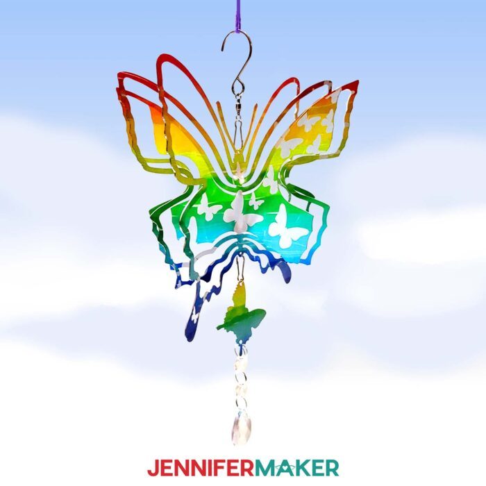 A butterfly-shaped wind spinner with a rainbow-patterned background and white butterflies. Learn how to design a wind spinner in Canva with this JenniferMaker tutorial.
