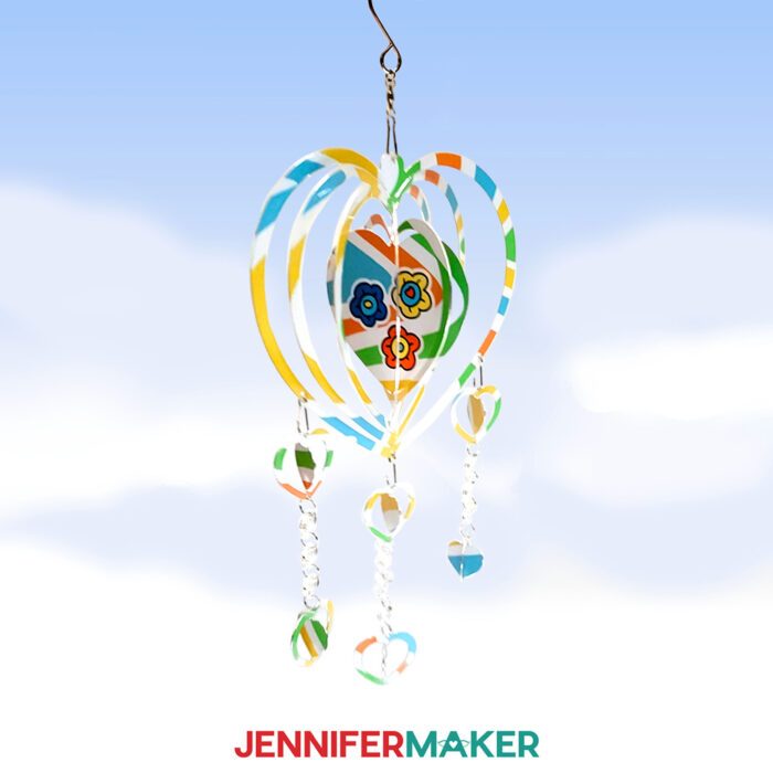 A heart-shaped wind spinner with a colorful swirl background and flowers in the center. 