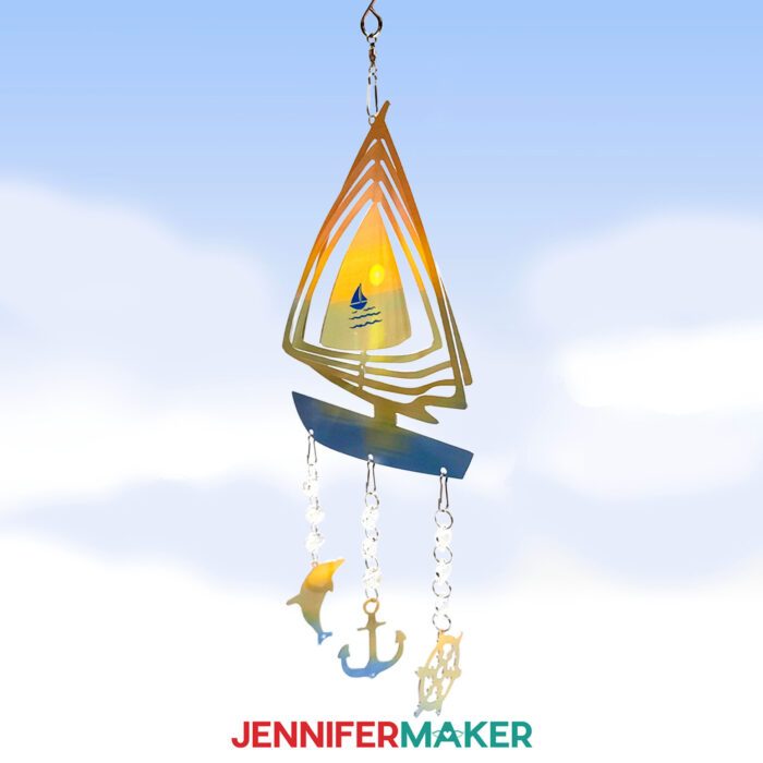 A sublimated sailboat wind spinner featuring a sunset on the sea and nautical dangle designs. 