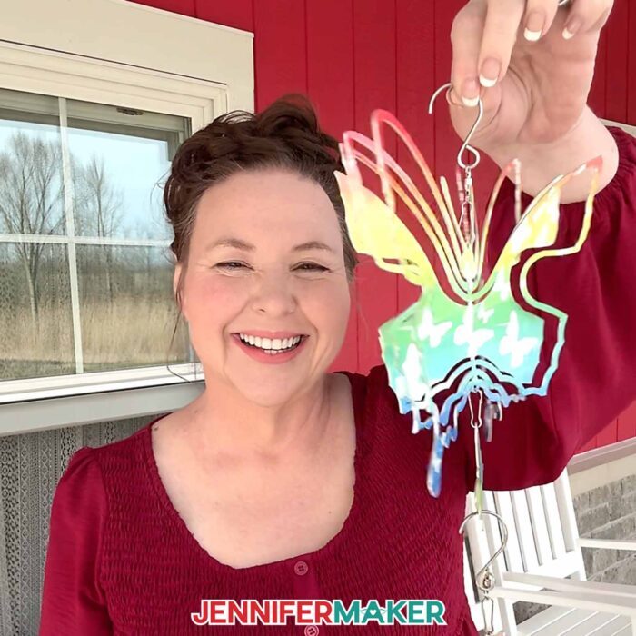 JenniferMaker holding up a sublimated butterfly-shaped wind spinner at the farm.