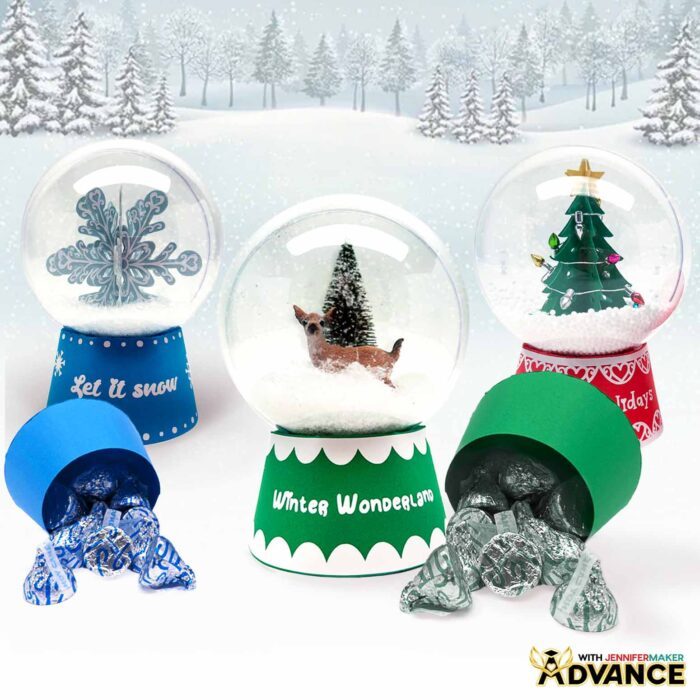 A set of three Snow Globe Gift Box designs, one with a snowflake, and two with pine trees. Two boxes are open, spilling chocolate candy onto the surface of the table