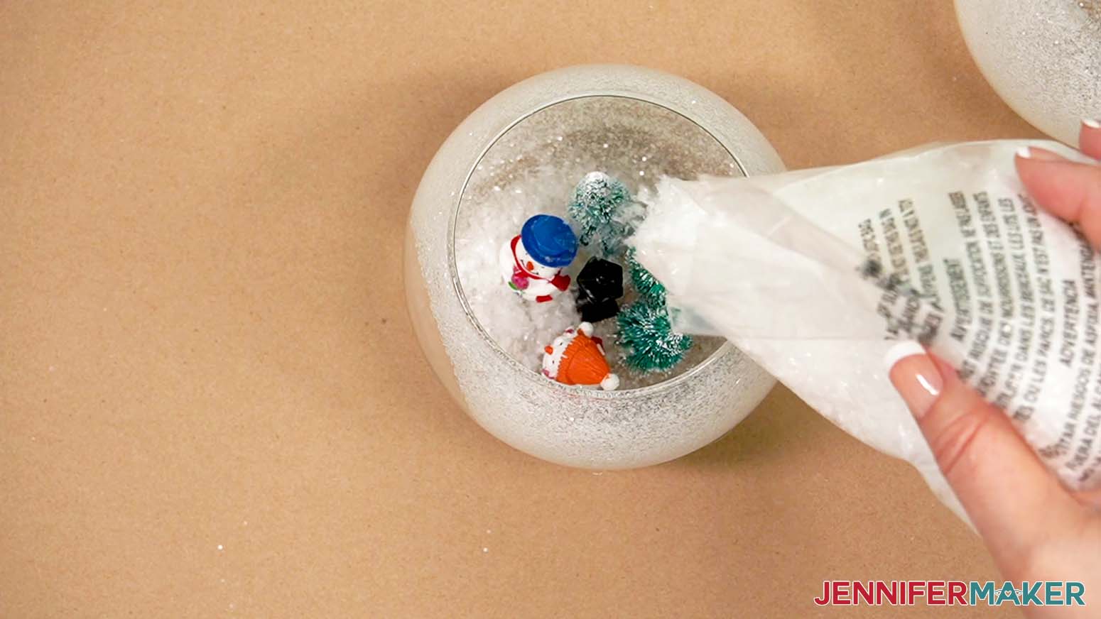 Add sparkling snow to the vase to barely cover the bottom on the figurines.