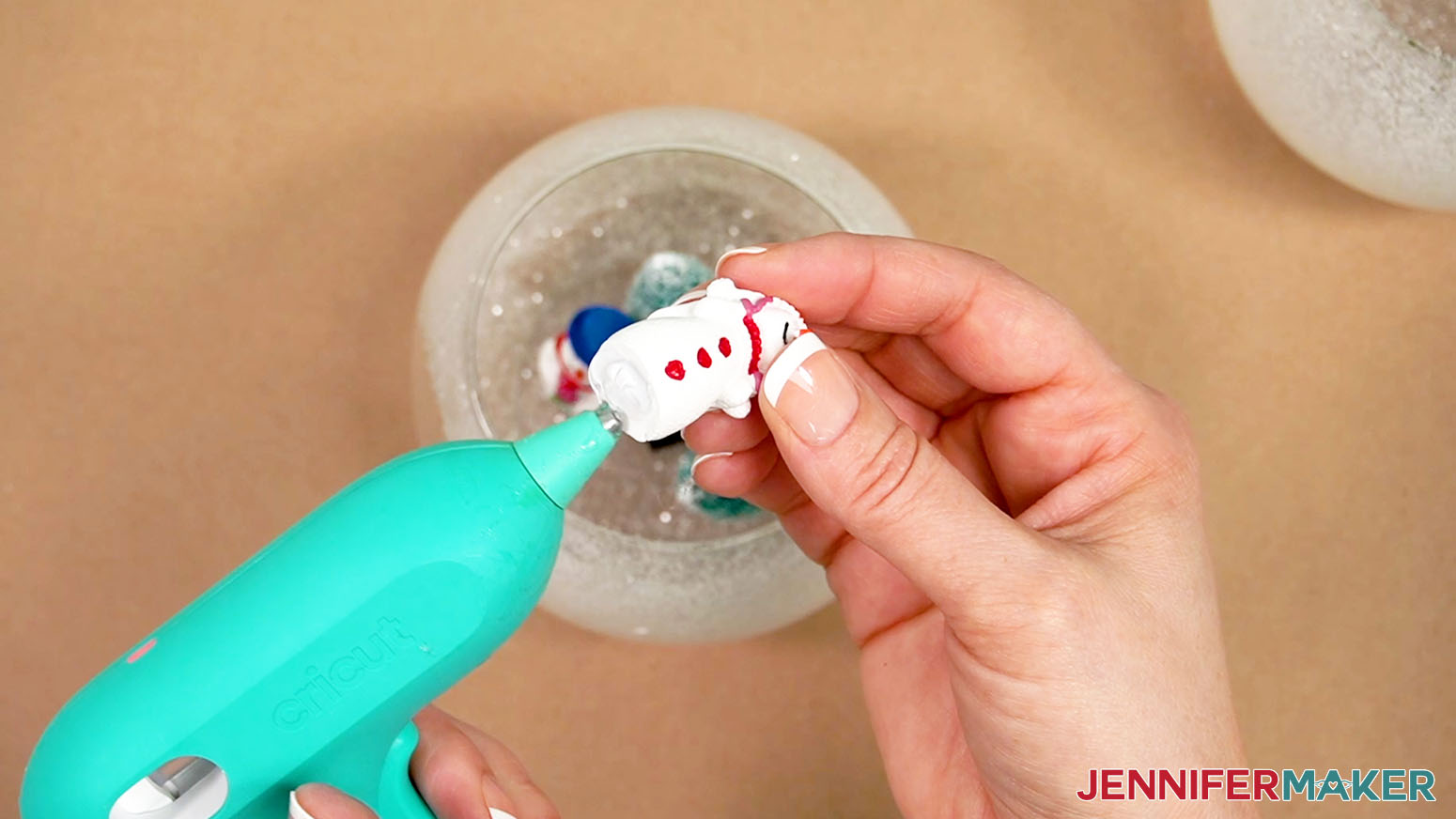 Apply hot glue to the bottom of the figurines and place them in the vase.