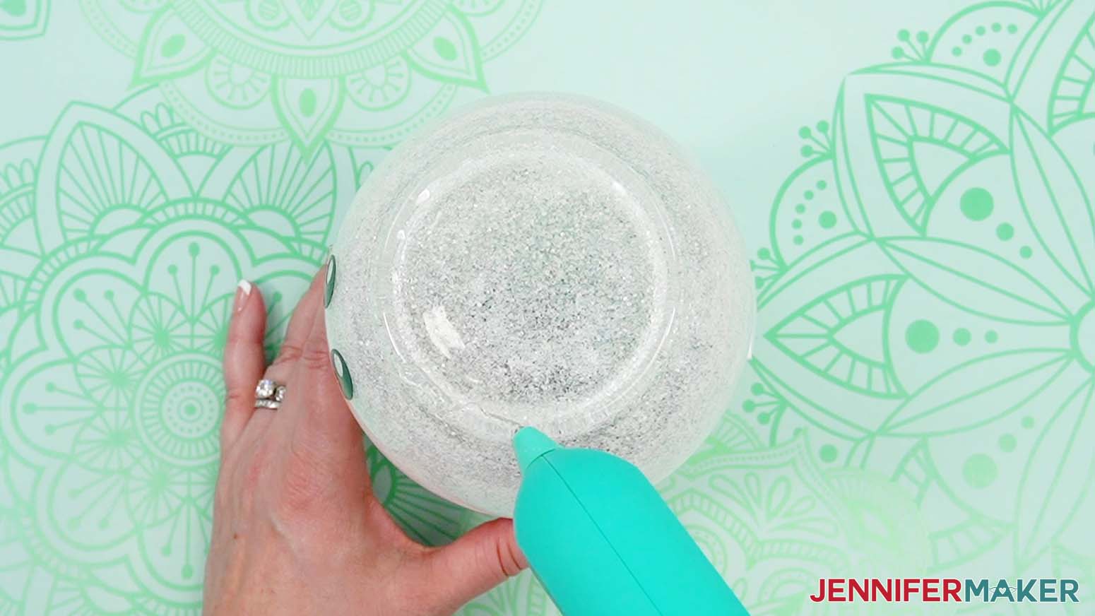 Apply hot glue around the top of the glass vase to adhere the top hat.