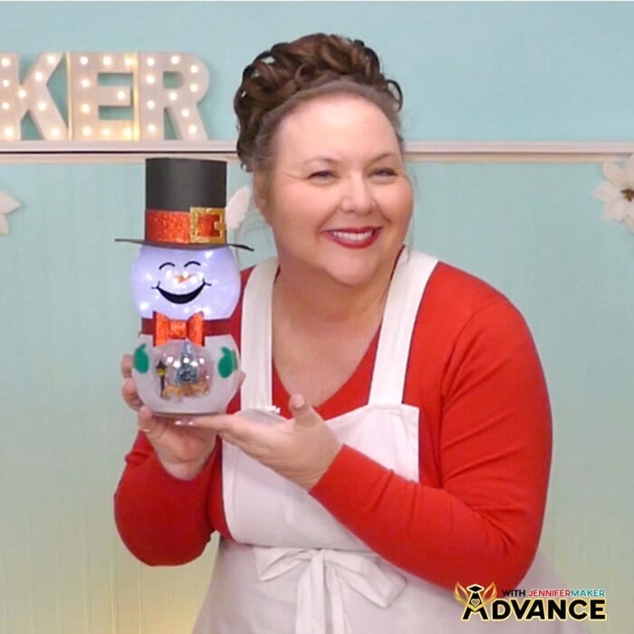Jennifer Maker shows off a completed smiling Snowman With Belly Scene lantern in her studio