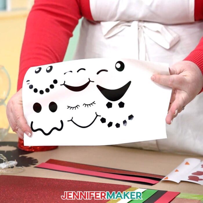 Jennifer shows the cut vinyl faces used to decorate the Snowman With Belly Scene craft