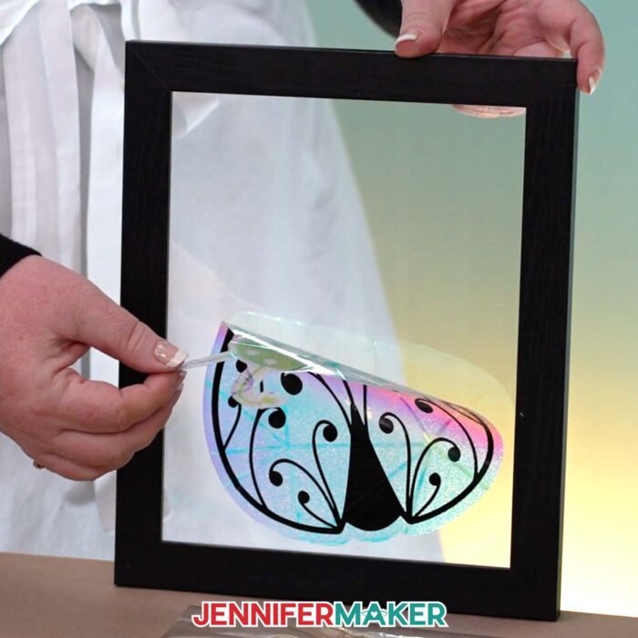 Jennifer peels a ladybug suncatcher window cling from a glass frame.