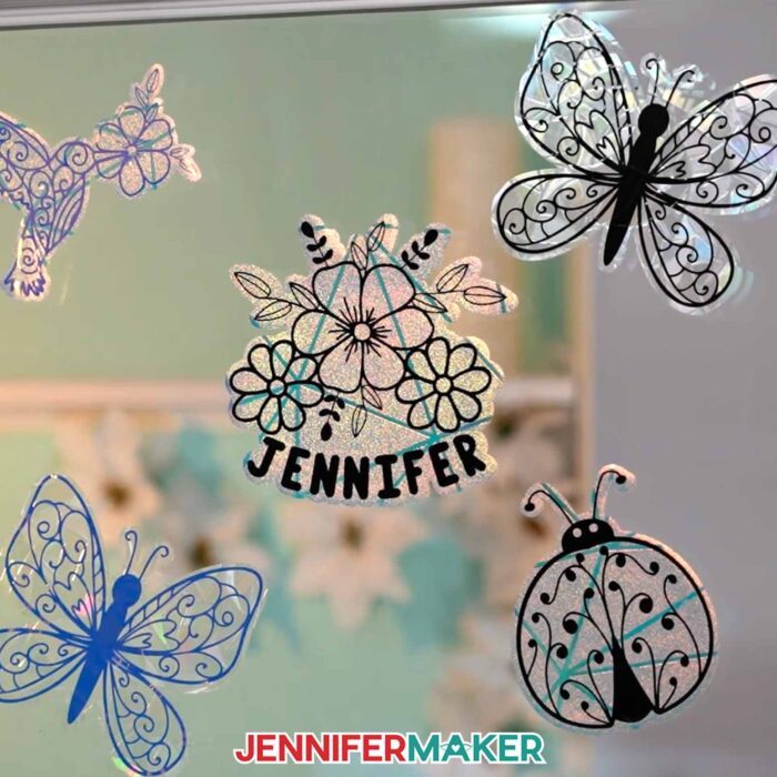Five shiny window clings on a glass pane. Learn to make these with JenniferMaker's free tutorial.