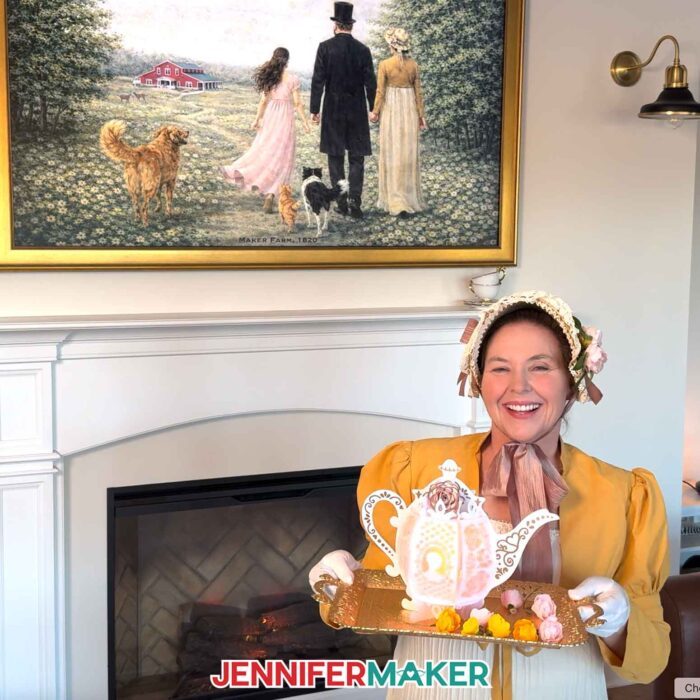 Jennifer Maker, dressed in Victorian finery, holds a tea tray with a hand-crafted teapot lantern and mini rolled flowers.