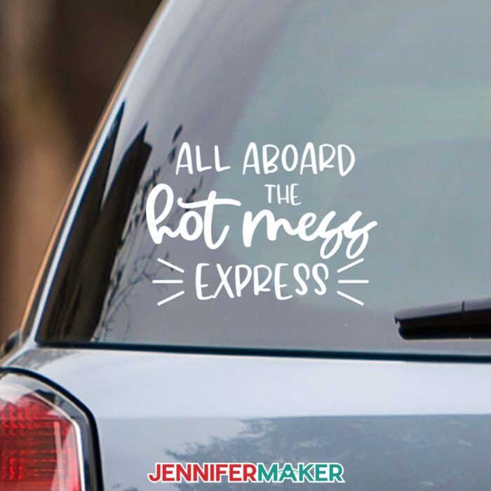 A white vinyl car decal reading All Aboard the Hot Mess Express on the back window of a car.