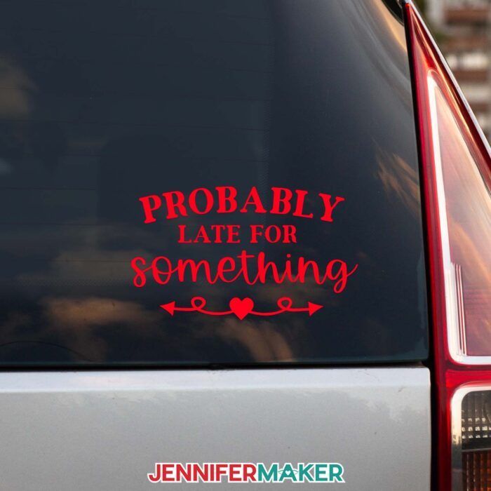 A red vinyl car decal reading Probably Late for Something on the back window of a car.
