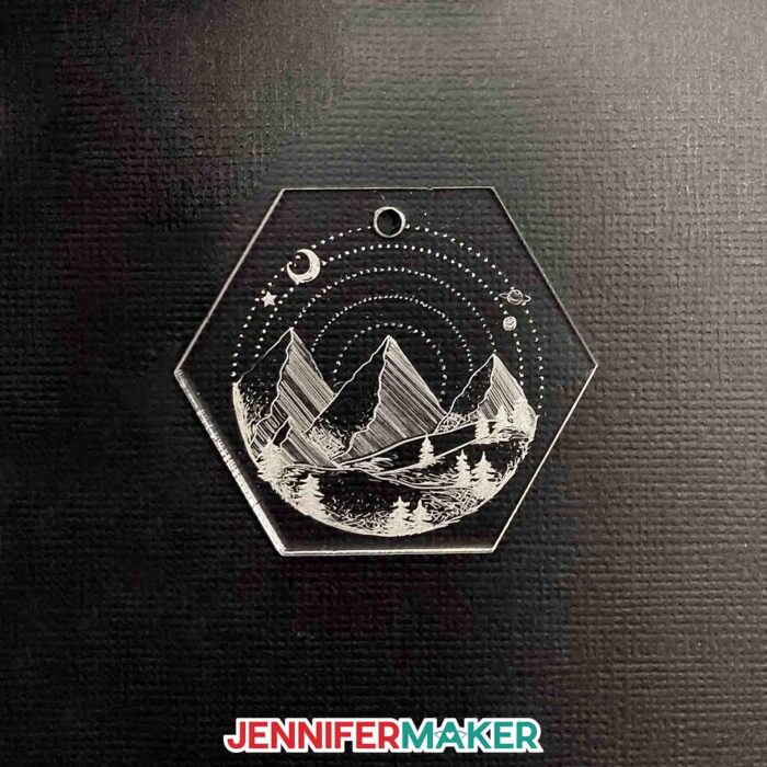 A hexagon acrylic engraved keychain with a mountain celestial design.