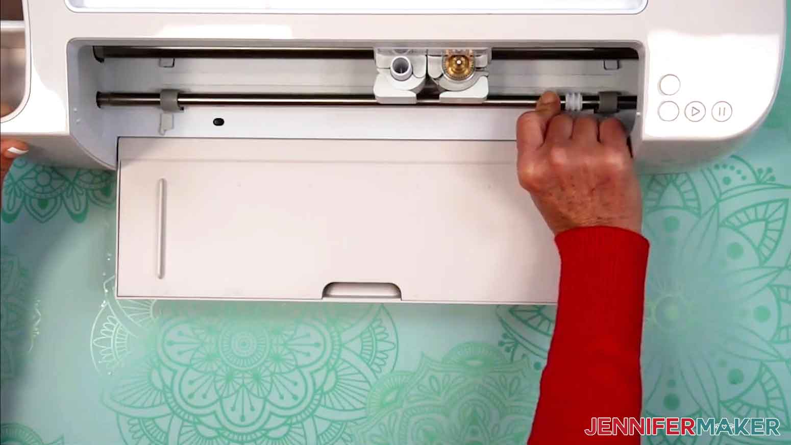 The Cricut is open and the star wheels are being moved to the far right side of the machine roller bar.